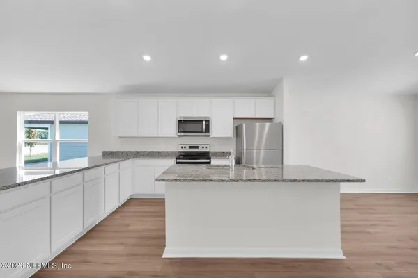 a large kitchen with stainless steel appliances granite countertop a large counter top and a stove top oven