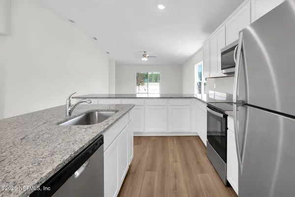 a kitchen with granite countertop a refrigerator stove and sink