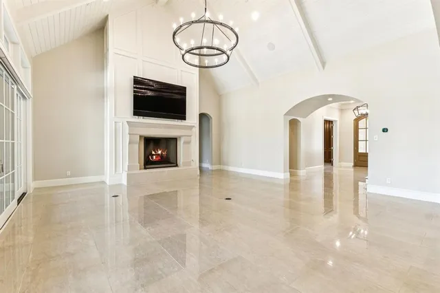 a view of an empty room with wooden floor fireplace and a window