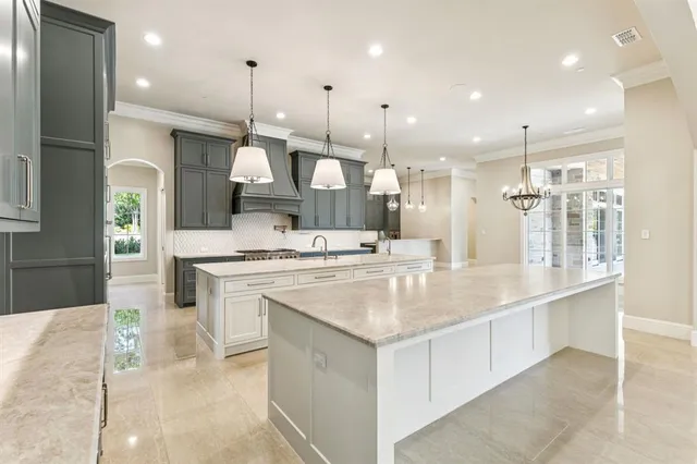 a large kitchen with a sink a counter top stainless steel appliances and cabinets