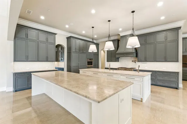 a large kitchen with a large counter top a refrigerator a sink and wooden cabinets