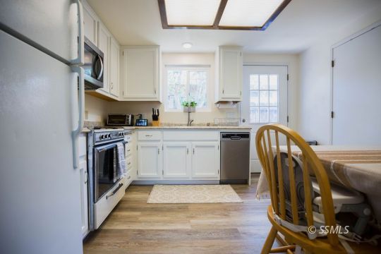 122 South Valley Street Ridgecrest, CA 93555 - Photo 9 of 26 a kitchen with stainless steel appliances granite countertop a stove a sink dishwasher and white cabinets with wooden floor