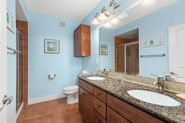 a bathroom with a granite countertop double vanity sink mirror and toilet