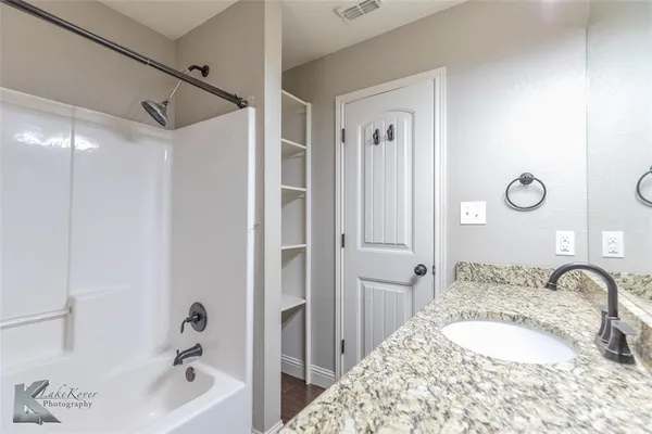 a bathroom with a granite countertop sink mirror and a bathtub