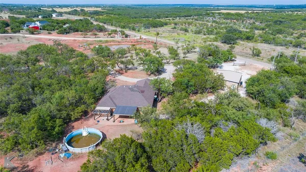 an aerial view of residential houses with outdoor space and trees
