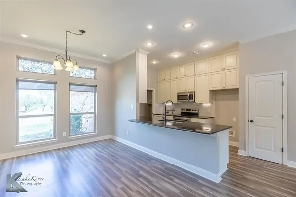 a kitchen with kitchen island granite countertop appliances cabinets and a wooden floor