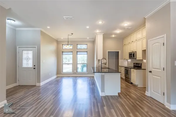 a large kitchen with a wooden floor and stainless steel appliances
