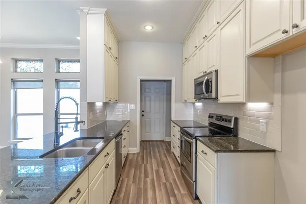 a kitchen with granite countertop a sink a counter space appliances and cabinets