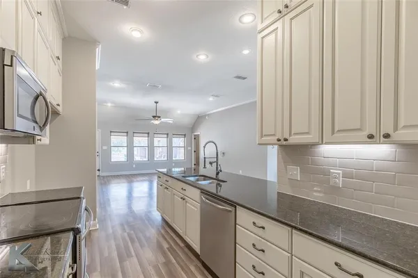 a kitchen with stainless steel appliances granite countertop a sink a stove and cabinets