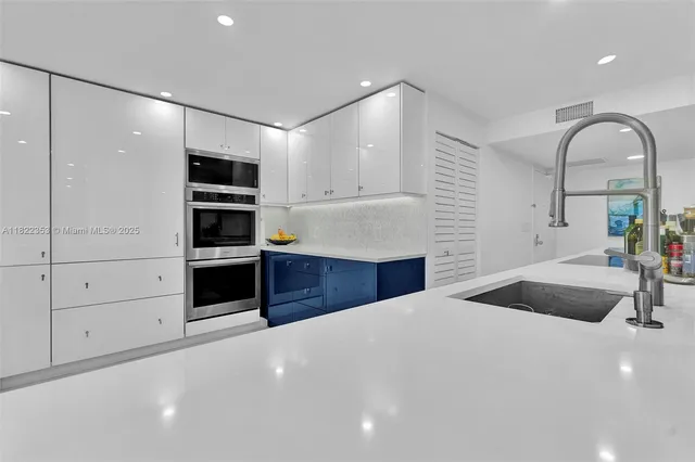 a large white kitchen with granite countertop a stove and a sink