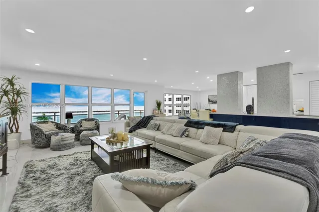 a living room with furniture kitchen view and large windows