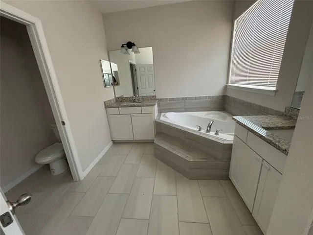 a bathroom with a granite countertop sink a toilet and bathtub
