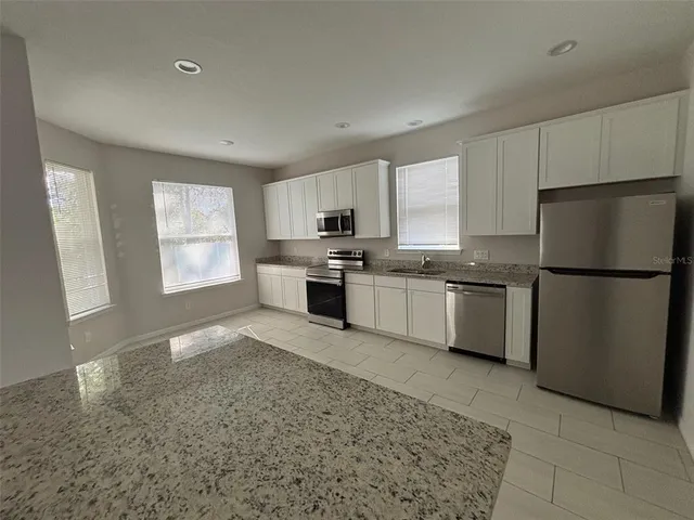 a kitchen with stainless steel appliances granite countertop a refrigerator sink stove microwave and cabinets