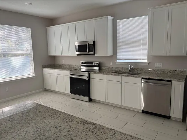 a kitchen with stainless steel appliances granite countertop a sink stove and microwave