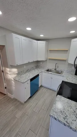a kitchen with granite countertop a sink and cabinets