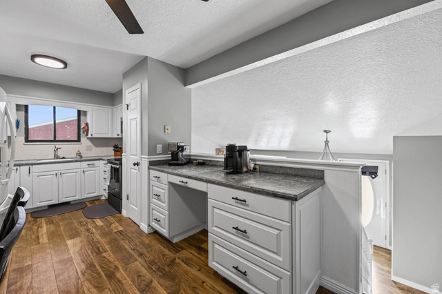 5896 South 3950th Street West Roy, UT 84067 - Photo 10 of 29 Kitchen featuring a textured ceiling, dark wood-style flooring, white cabinets, a ceiling fan, and dark countertops