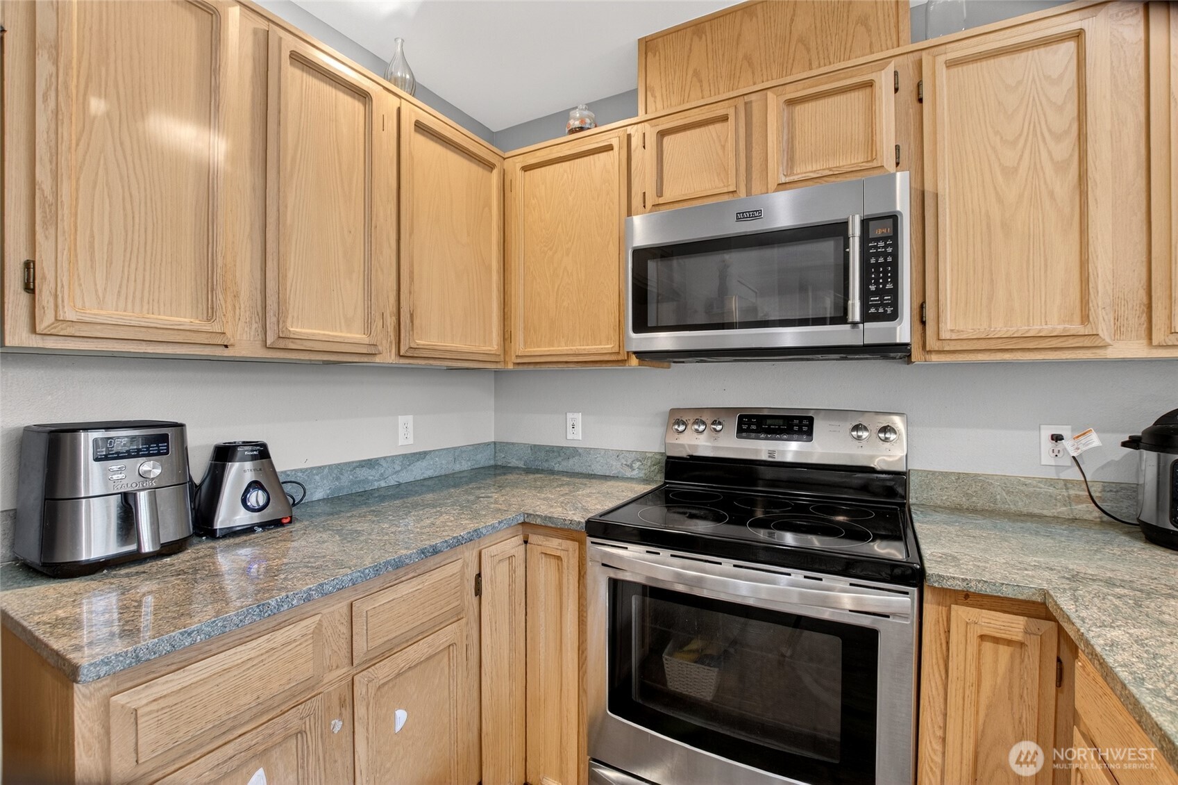 6615 South 239th Place, Unit R109 Kent, WA 98032 - Photo 18 of 40 a kitchen with granite countertop a stove top oven microwave and cabinets