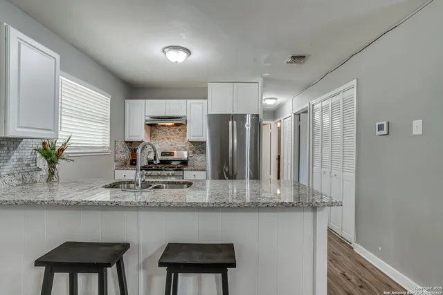 a kitchen with stainless steel appliances granite countertop a kitchen island a stove a sink and a refrigerator