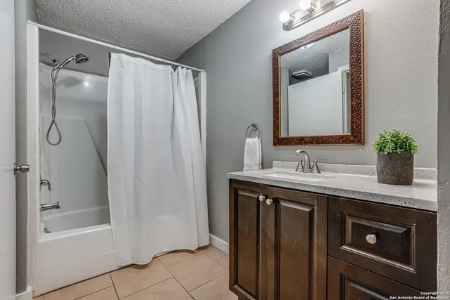 a bathroom with a granite countertop sink mirror and a bathtub
