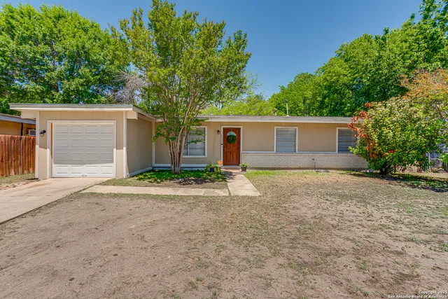 front view of house with a yard and trees all around