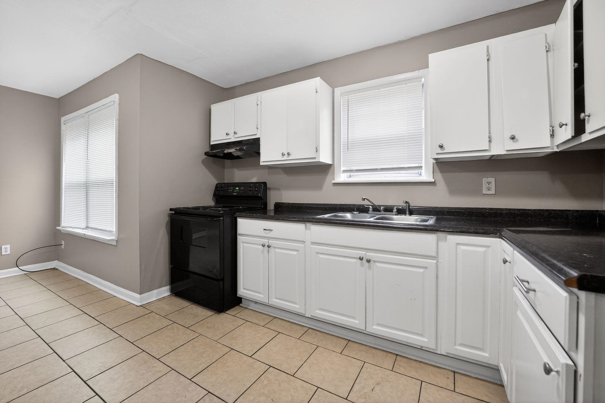 4553 Neely Road Memphis, TN 38109 - Photo 5 of 33 a kitchen with granite countertop white cabinets and black appliances
