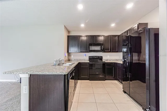 a kitchen with kitchen island granite countertop a refrigerator and a stove top oven