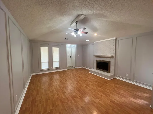 a view of empty room with a fireplace and wooden floor