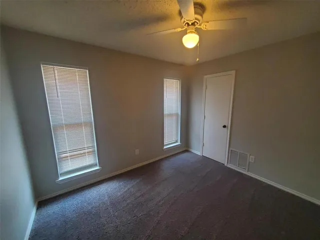 an empty room with windows and fan