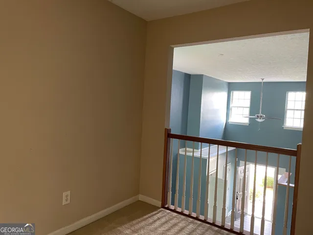 a view of a hallway with wooden floor and a bathroom