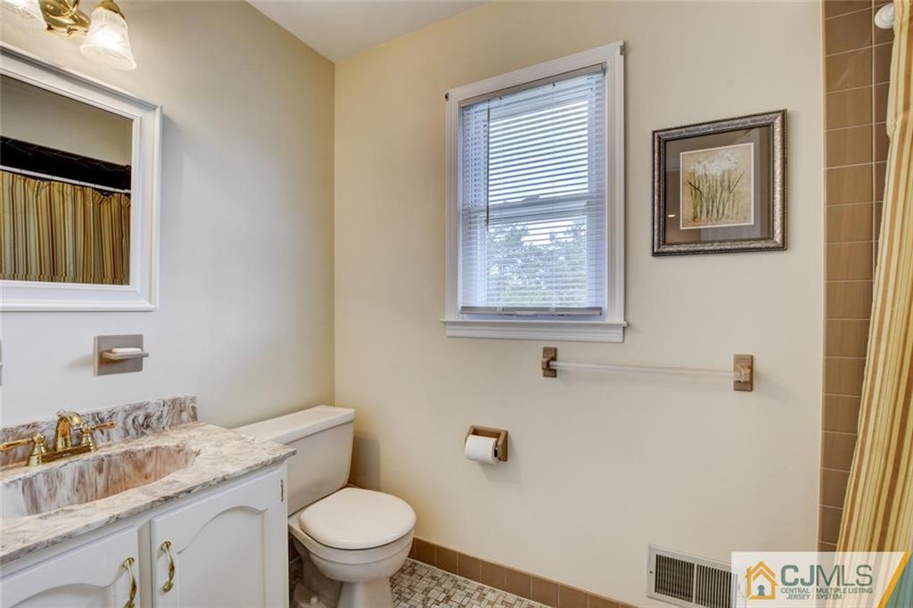 8 Vince Road Somerset, NJ 08873 - Photo 13 of 24 a bathroom with a granite countertop toilet a sink and a mirror