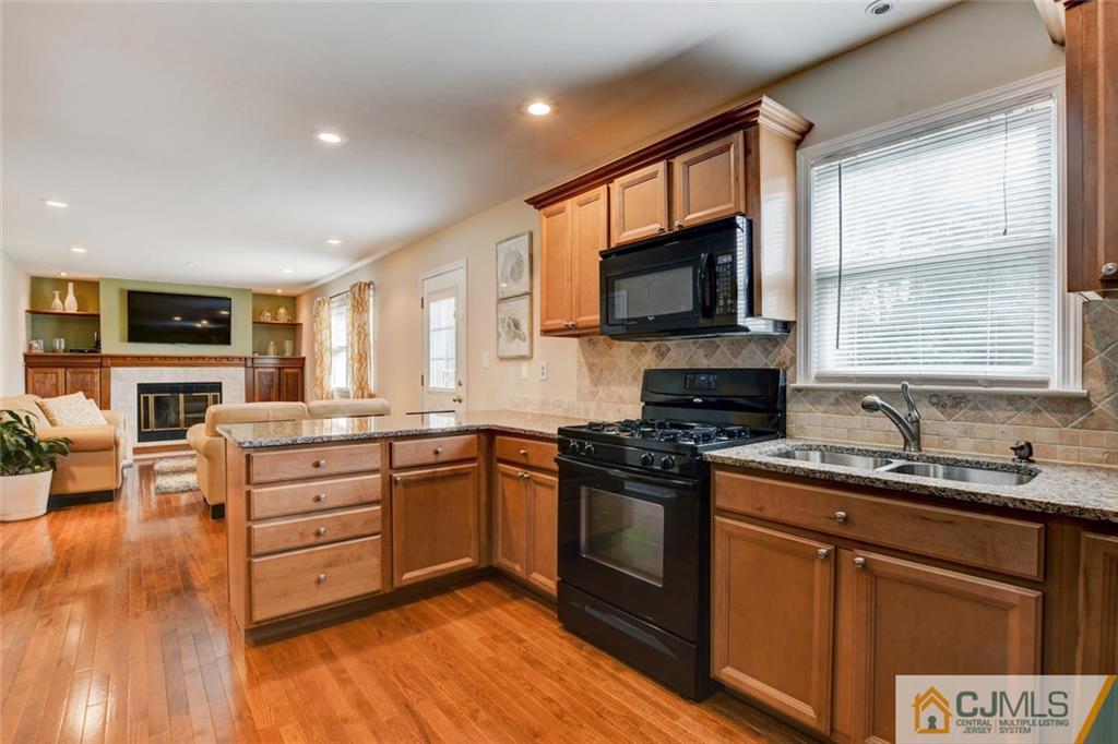 8 Vince Road Somerset, NJ 08873 - Photo 4 of 24 a kitchen with stainless steel appliances granite countertop a stove top oven a sink dishwasher a dining table and chairs with wooden floor