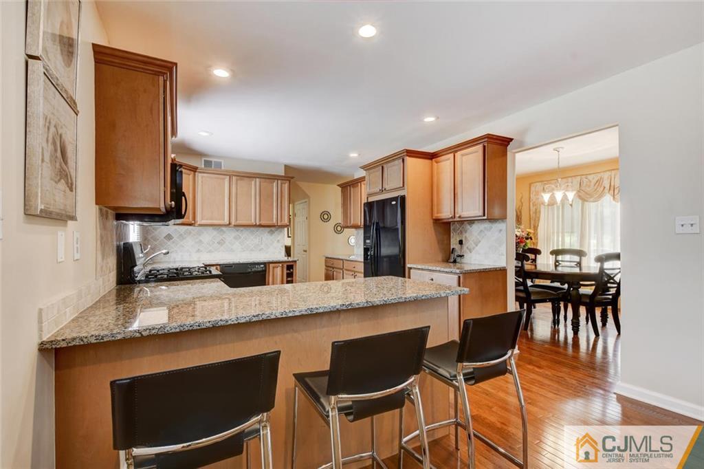 8 Vince Road Somerset, NJ 08873 - Photo 5 of 24 a kitchen with stainless steel appliances granite countertop a stove a sink a microwave a dining table and chairs with wooden floor