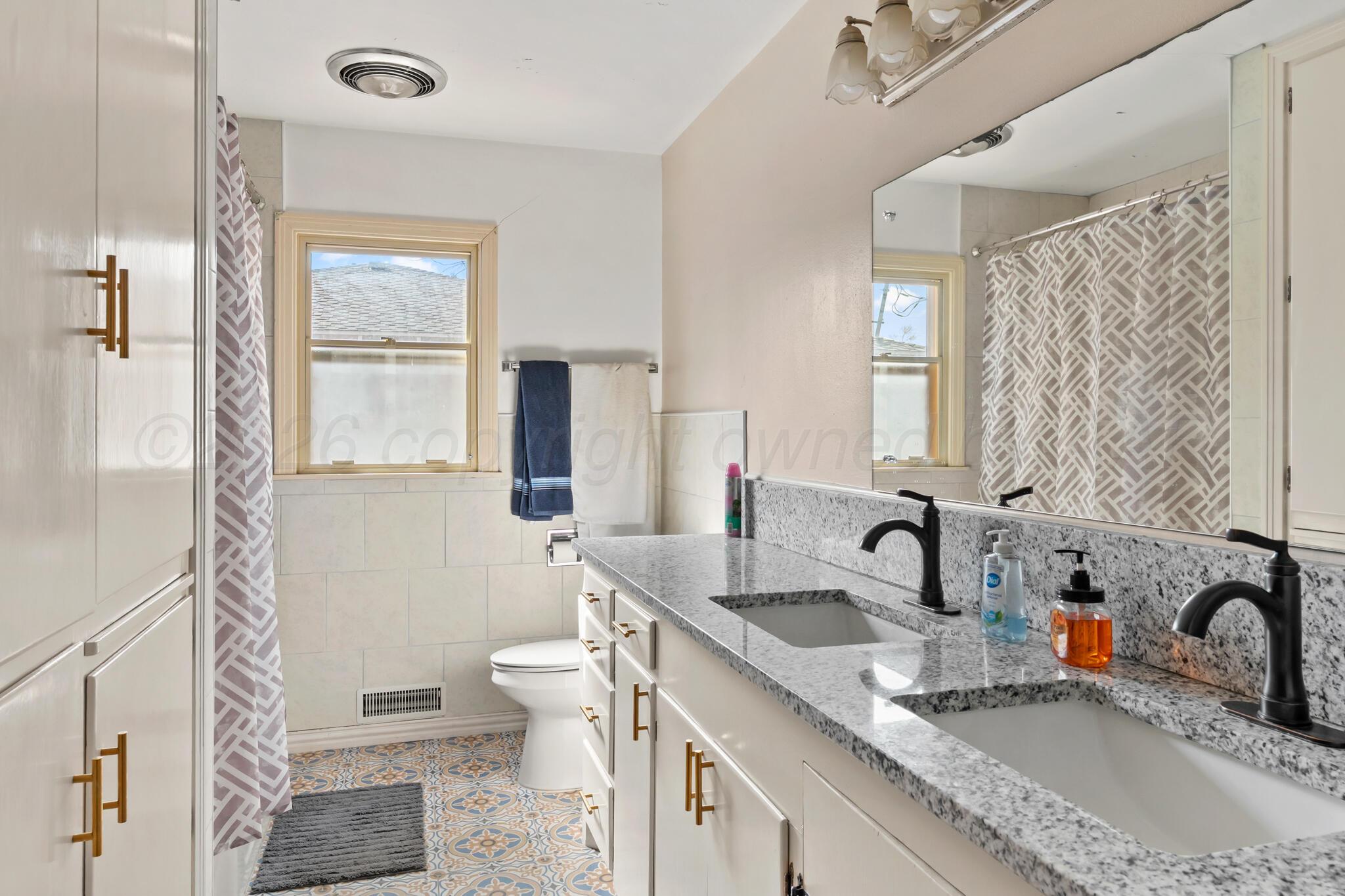 2217 Peach Tree Street Amarillo, TX 79109 - Photo 20 of 26 a bathroom with a granite countertop sink a toilet and a window