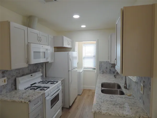 a kitchen with granite countertop a sink stove and refrigerator
