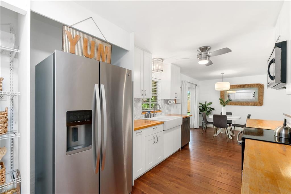 3543 Corana Way Naples, FL 34105 - Photo 10 of 26 a kitchen with stainless steel appliances granite countertop a refrigerator a stove and a dining table with wooden floor