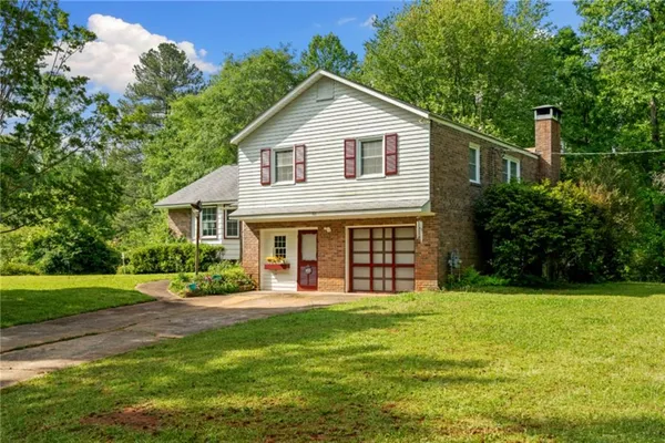 a front view of a house with a yard and trees