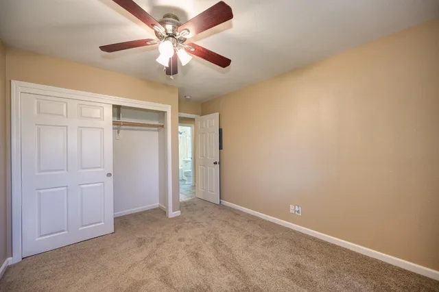 an empty room with closet and a chandelier fan