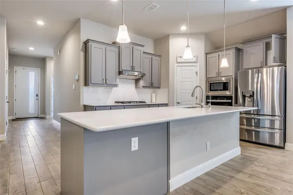 a large kitchen with stainless steel appliances kitchen island granite countertop a stove a sink and a refrigerator