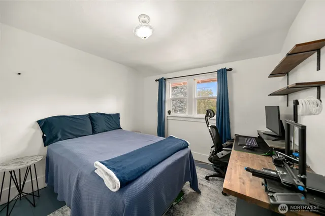 a bedroom with a bed and a flat tv screen on the dresser