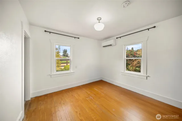 a view of an empty room with a window and wooden floor