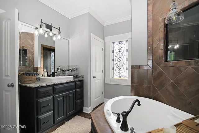 a bathroom with a tub a sink and mirror