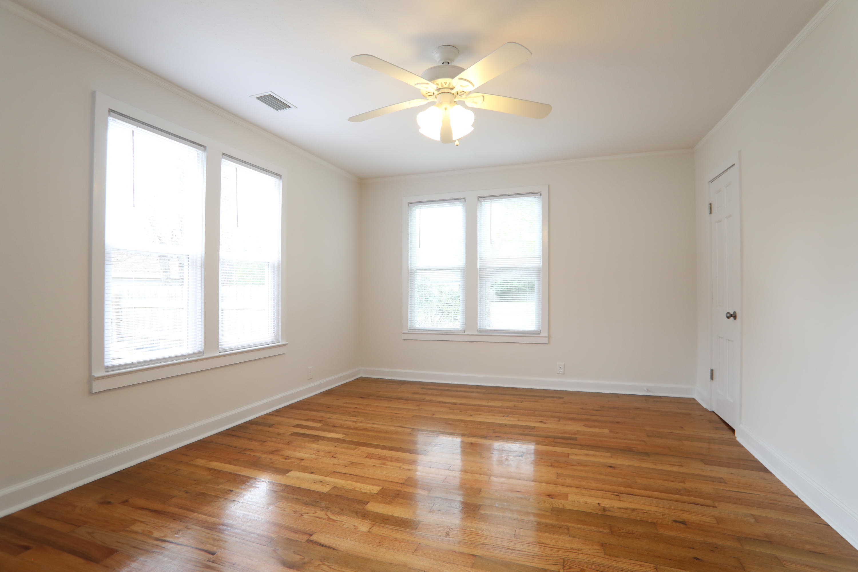 302 East 2nd Avenue Crestview, FL 32536 - Photo 5 of 12 an empty room with wooden floor and windows