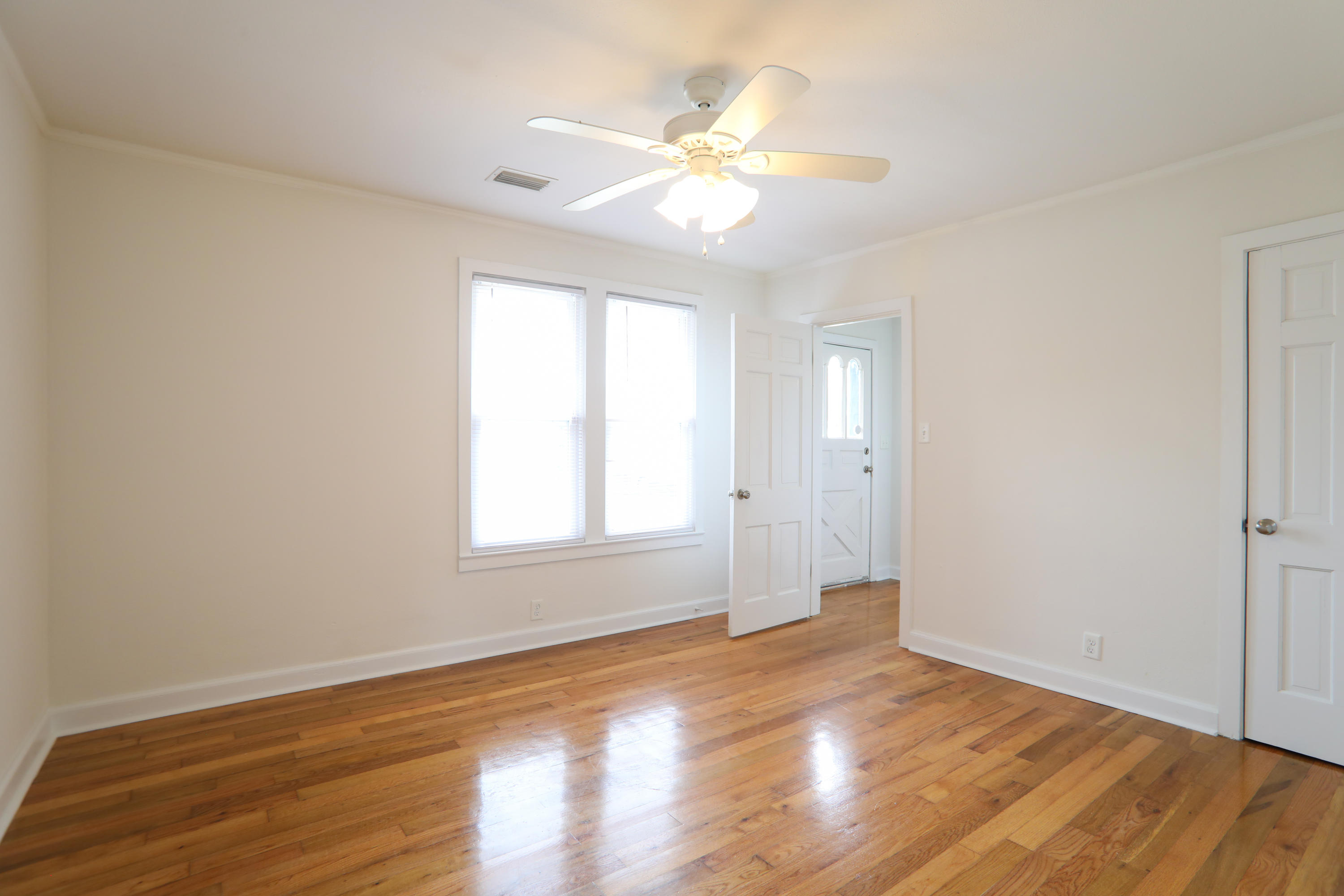 302 East 2nd Avenue Crestview, FL 32536 - Photo 6 of 12 an empty room with wooden floor and windows