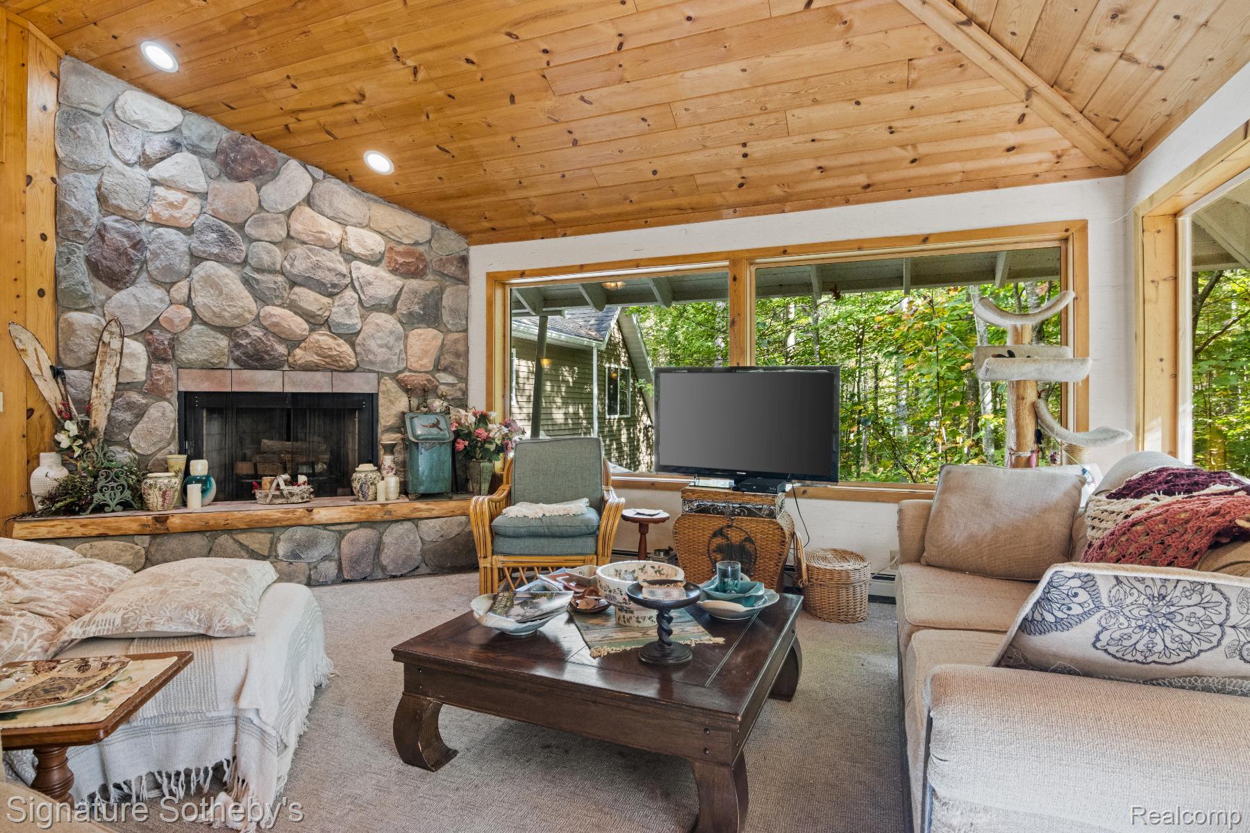 11436 Lakeview Road Northeast Kalkaska, MI 49646 - Photo 6 of 29 Carpeted living room featuring wood ceiling, lofted ceiling, and an outdoor stone fireplace