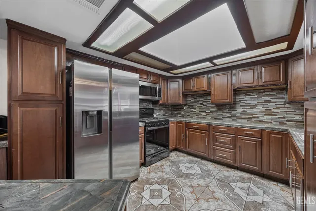 a kitchen with stainless steel appliances granite countertop a refrigerator a oven a sink with granite countertops and cabinets