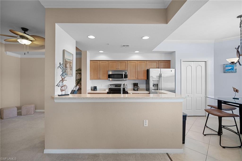 10285 Heritage Bay Boulevard, Unit 817 Naples, FL 34120 - Photo 21 of 42 a kitchen with stainless steel appliances granite countertop a refrigerator and a stove top oven