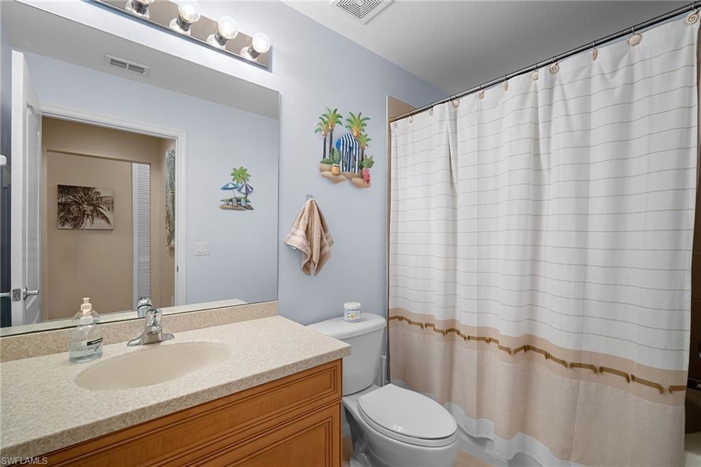 10285 Heritage Bay Boulevard, Unit 817 Naples, FL 34120 - Photo 10 of 42 a bathroom with a sink a toilet and shower curtain