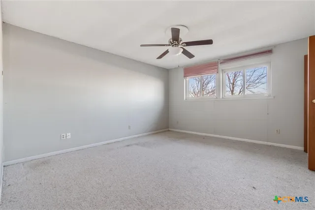 an empty room with ceiling fan and windows