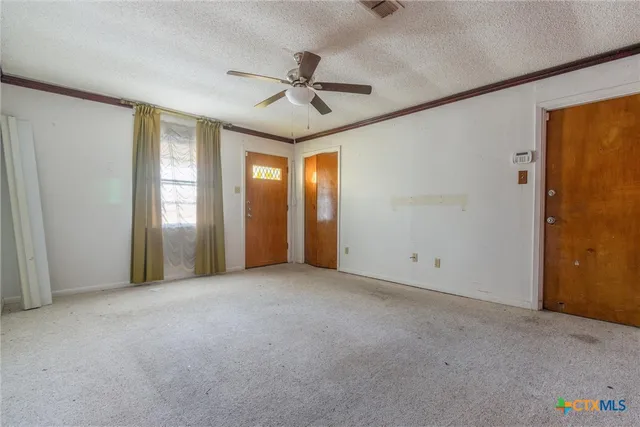 an empty room with ceiling fan and windows