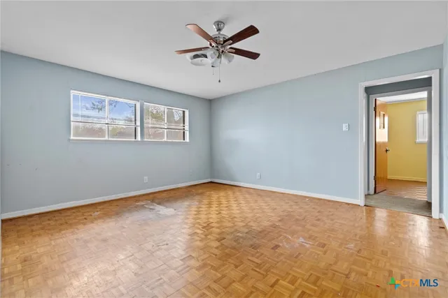 an empty room with a ceiling fan and window